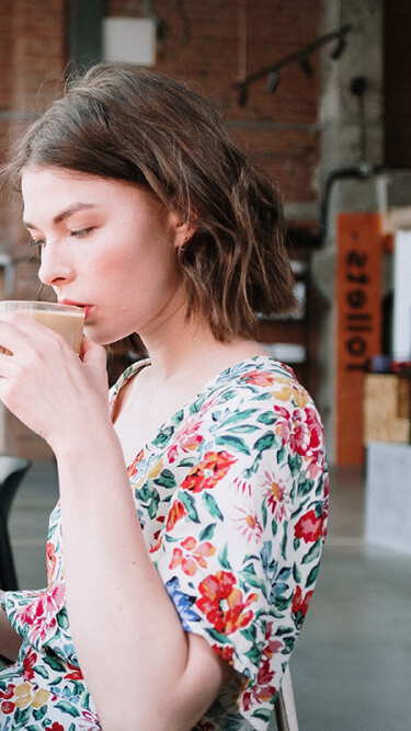 カフェのテーブルでコーヒーを飲みながら本を読んでいる女性